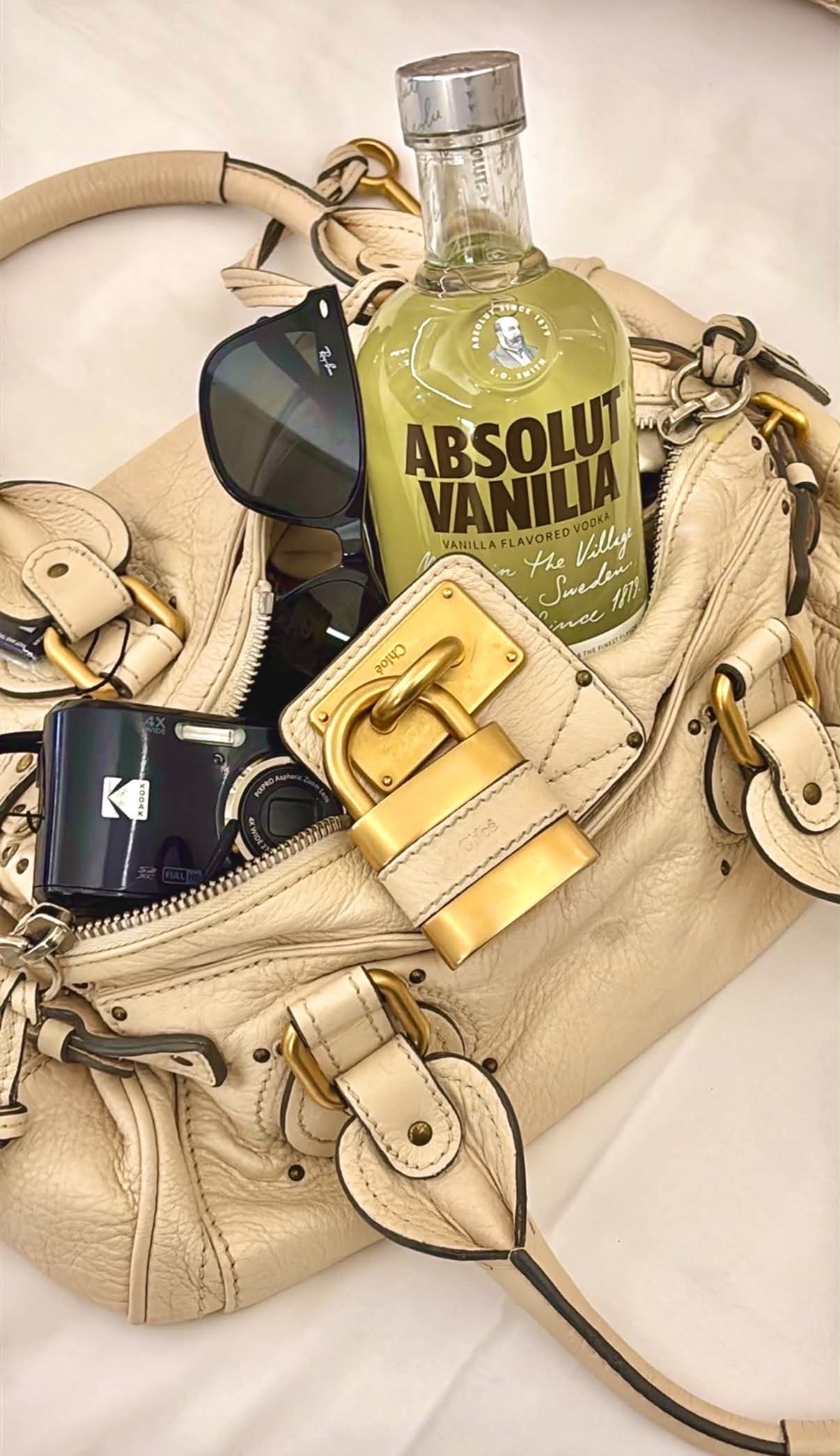 Cream Chloé Paddington bag with brushed gold padlock, styled with sunglasses and a compact camera