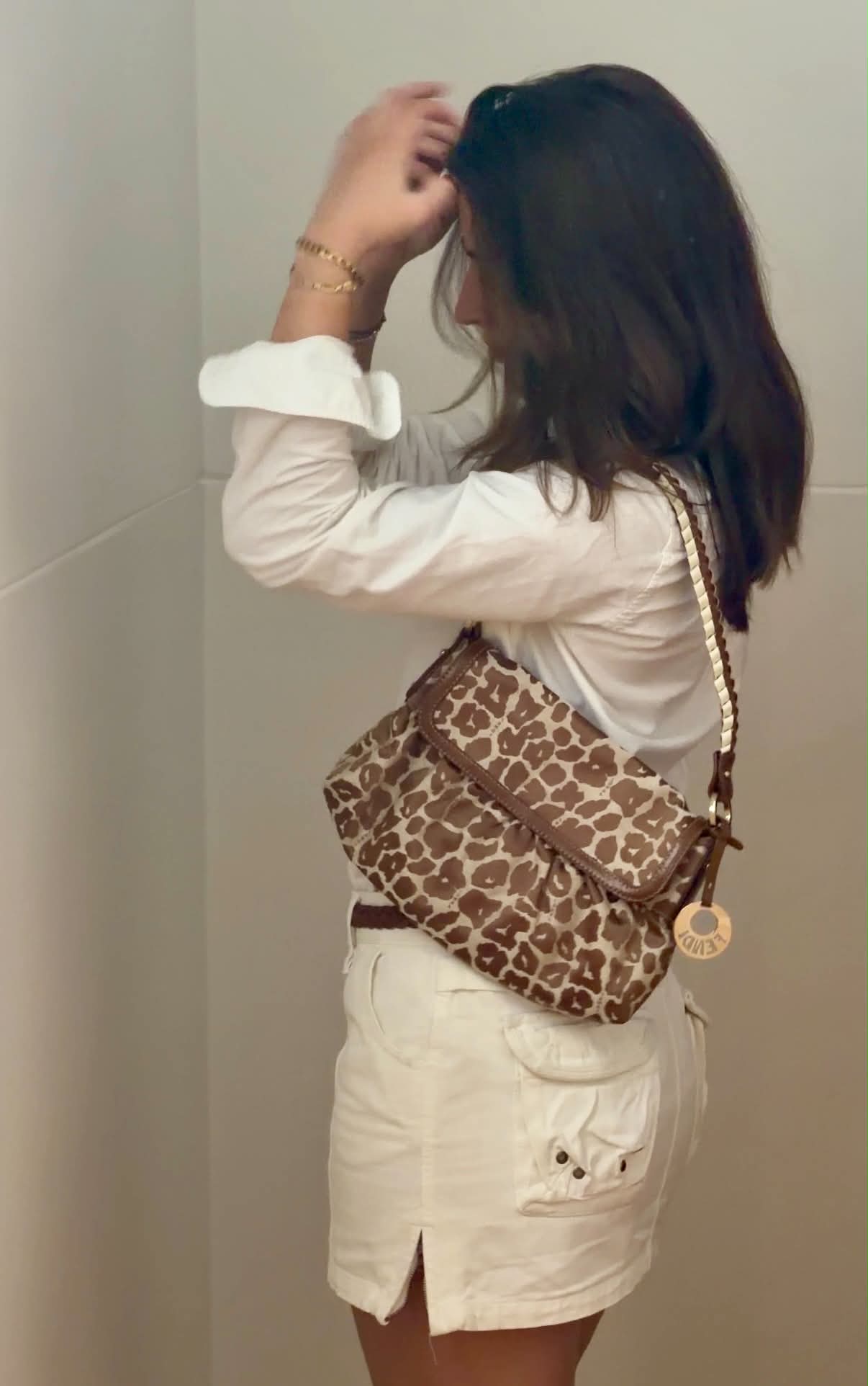 A leopard print Fendi shoulder bag worn over a white shirt and cream skirt