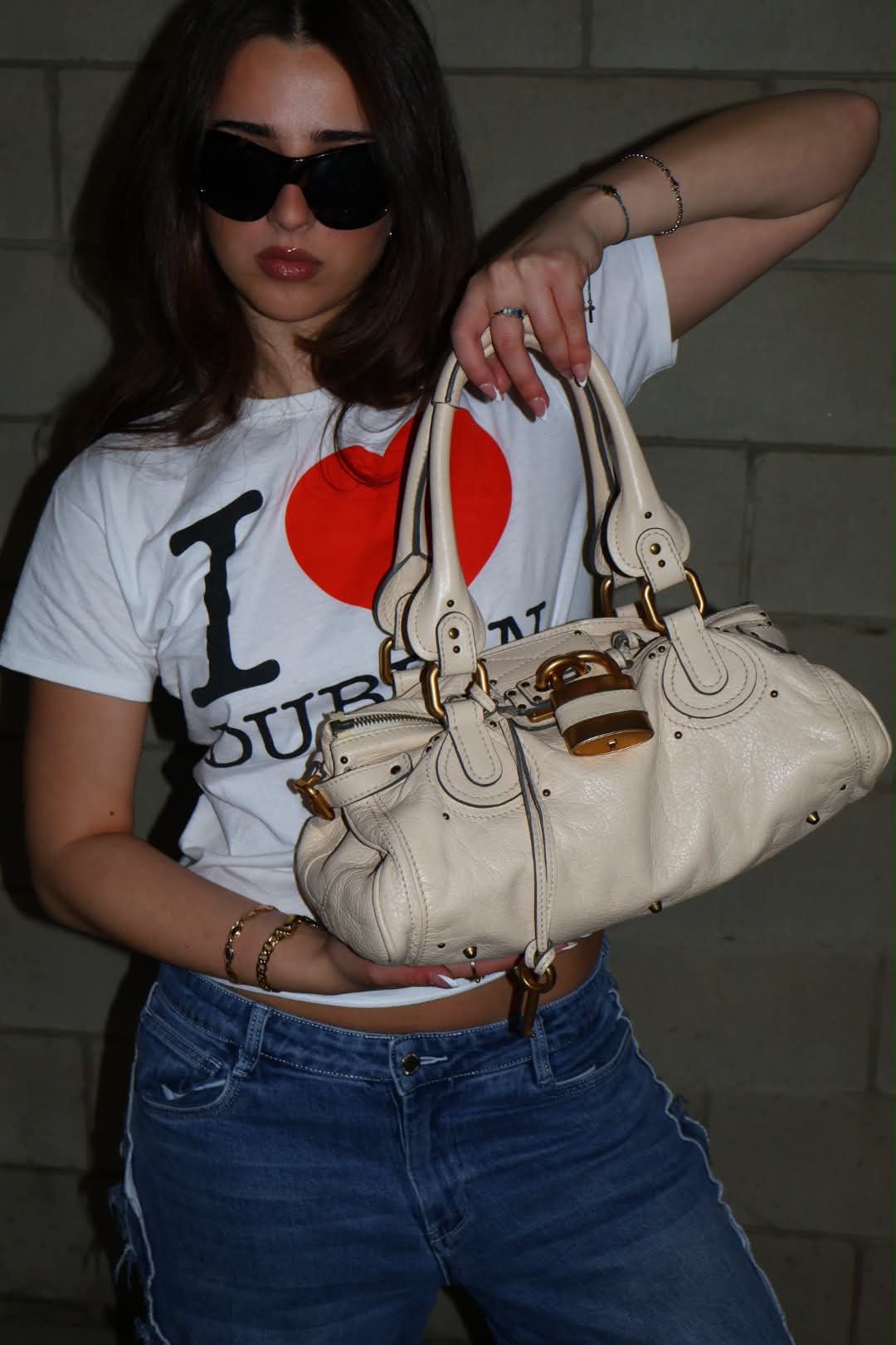 Full-length shot holding the cream Paddington in an I heart Dublin tee and faded jeans