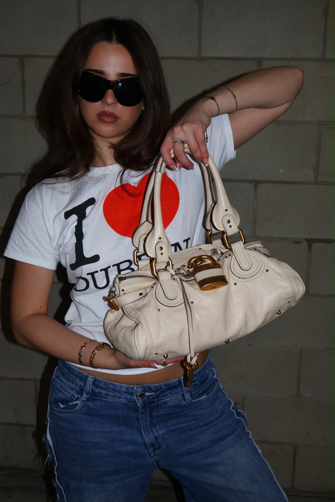A cream Chloé Paddington held across an I heart Dublin tee and faded jeans