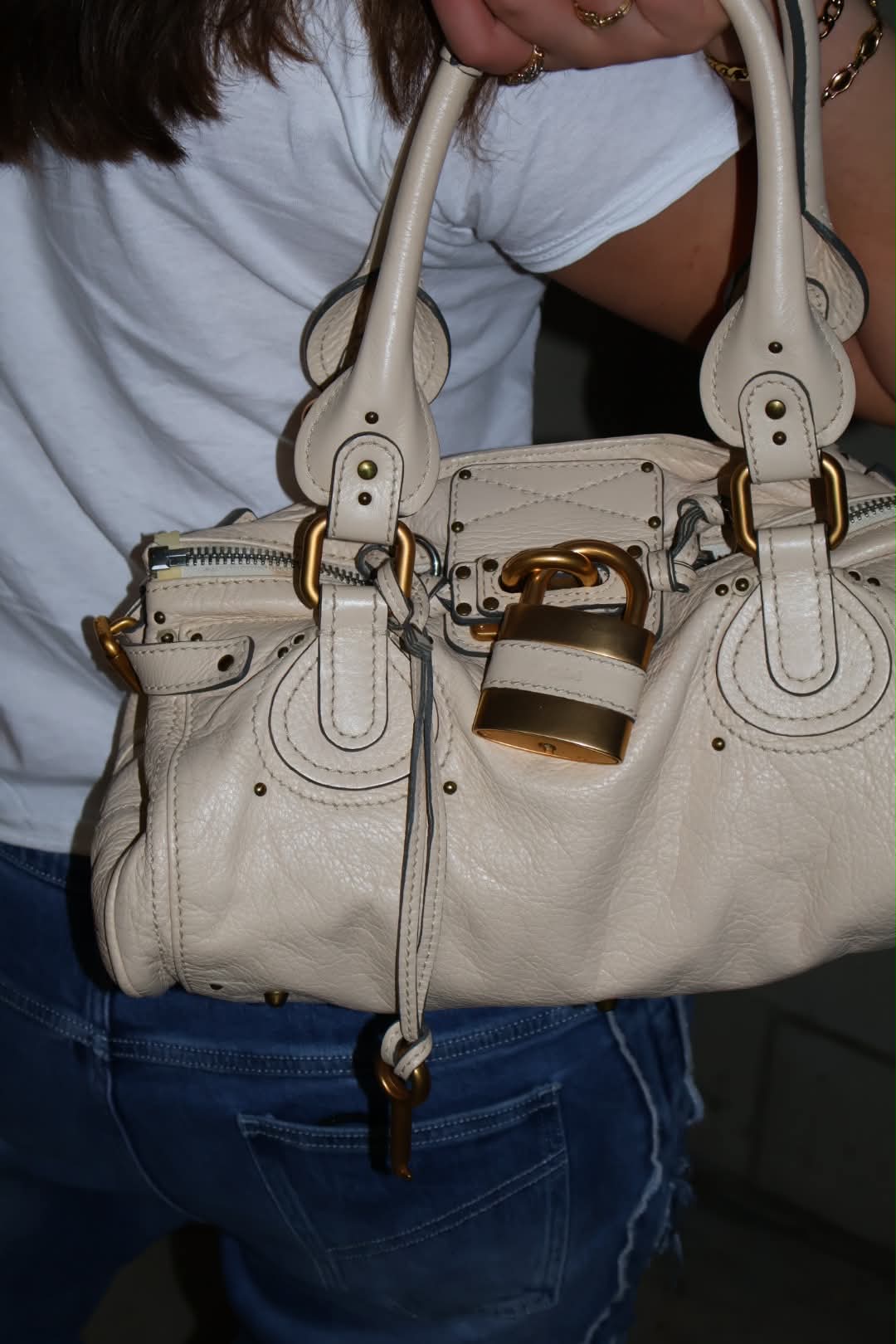 Close detail of the Chloé Paddington's brushed gold padlock and cream pebbled leather